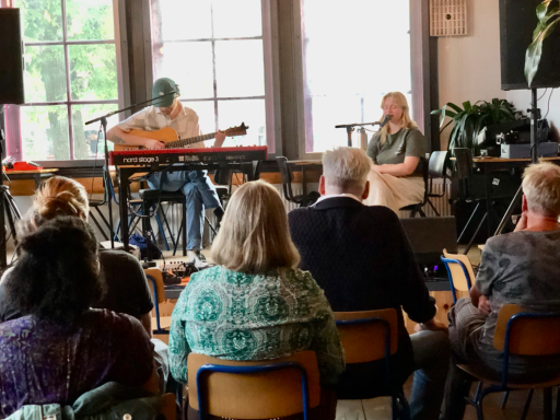 Twee muzikanten optreden voor een publiek in een intieme setting.