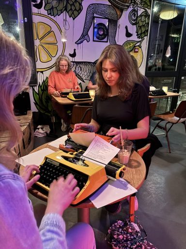 Drie vrouwen op een typemachine met een kleurrijke achterwand.