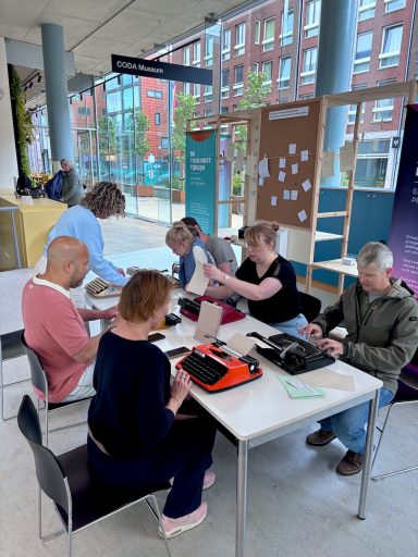 Type-in bij CODA vijf mensen achter een typemachine