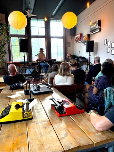 Een artiest optredend voor een publiek in een sfeervol café met lampionnen.